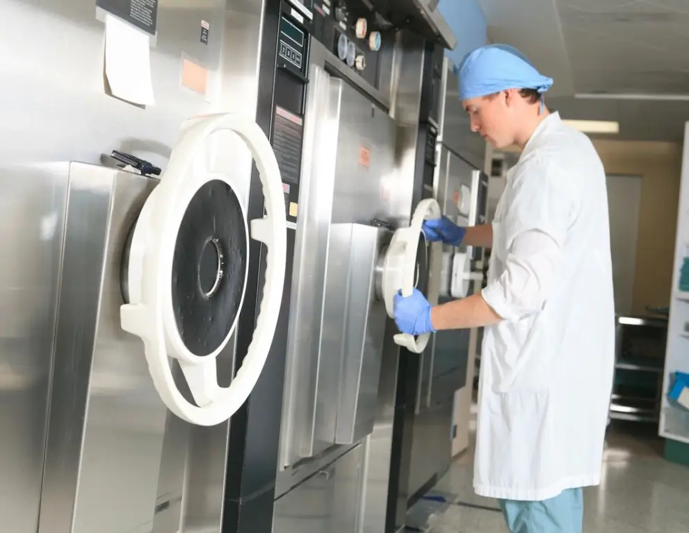 A man in white lab coat cleaning an oven.