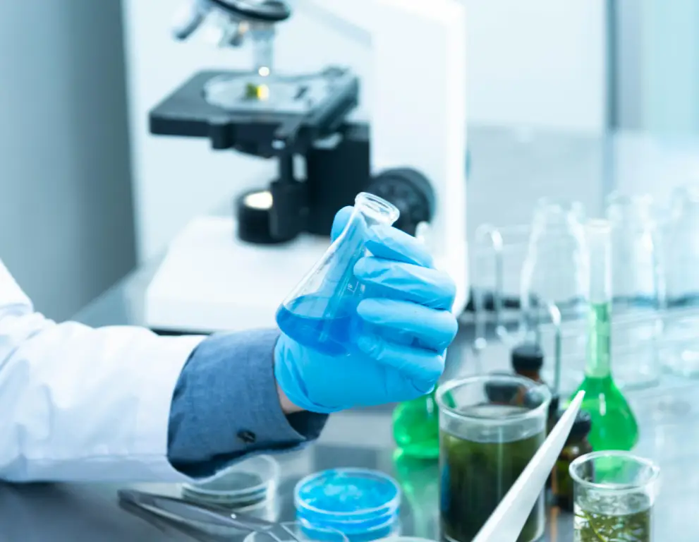 A person in lab coat holding a glass.