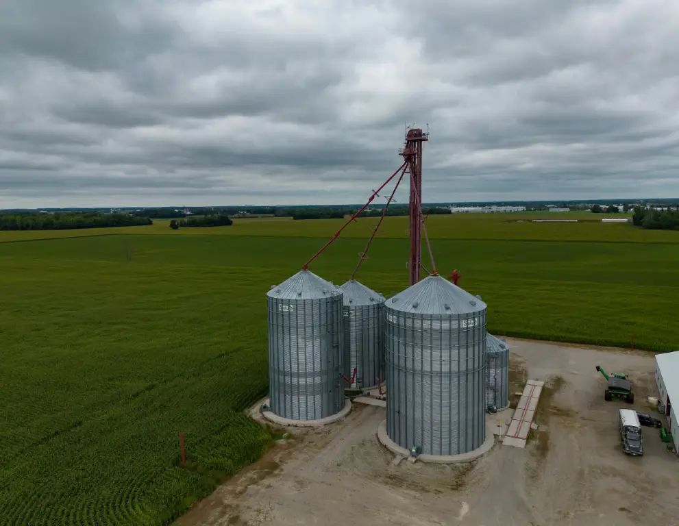 A large field with three grain silos in the middle of it.